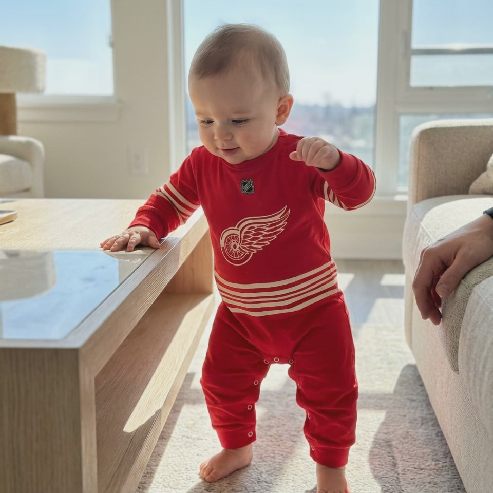 Detroit Red Wings - Hockey Baby Onesie Jumpsuit - Baby taking first steps whiule wearing a detroit red wings hockey baby onesie jumpsuit | Dash Racegear